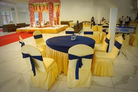 Round-table banquet seating with yellow and navy chair covers inside the hall