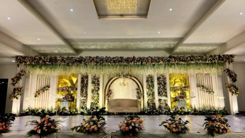 Green and white floral reception stage with hanging blooms in the convention hall, Shamshabad