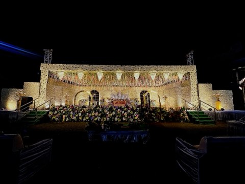 Illuminated open-air stage with truss lighting on the lawn for an evening reception