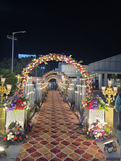 Pink floral entrance arches over a red carpet walkway leading into the venue at night