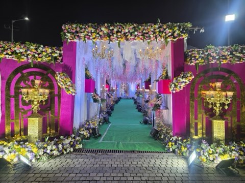 Pink and gold decorated entrance gate with green carpet at Jaithri Grand Convention, NH-44