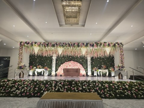Pink rose reception stage with green floral wall and chandelier at the reception hall in Shamshabad