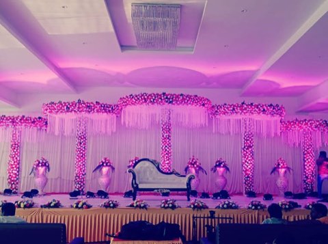 Reception stage with pink floral decor and mood lighting at the reception hall in Shamshabad