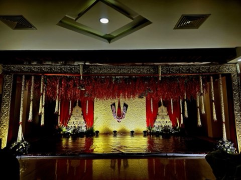 Traditional red and gold wedding stage with hanging marigold strings at the function hall on NH-44