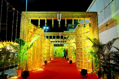 Gold-lit wedding entrance arch with red carpet outside the hall