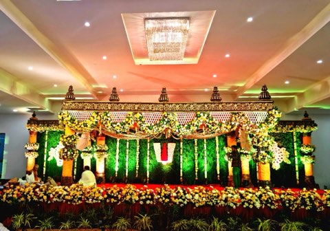 Wedding mandap with green floral wall and chandelier at Jaithri Grand Convention, Shamshabad
