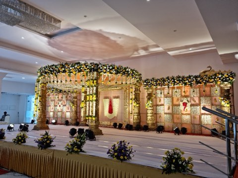 Wedding mandap dressed in marigold garlands and maroon backdrop at Jaithri Grand Convention