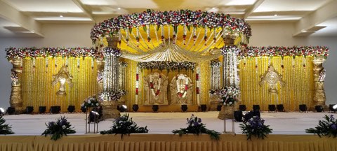 Marigold-draped wedding mandap on the main stage of the convention hall in Shamshabad