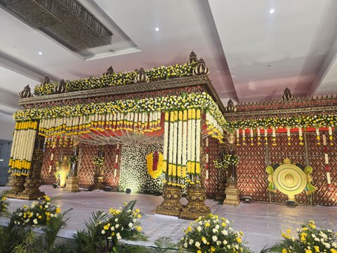 White and yellow floral wedding stage inside the air-conditioned hall at Jaithri Grand
