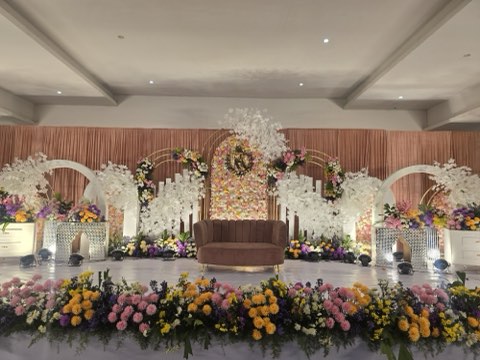 Wide view of a white and peach floral wedding stage in the air-conditioned hall at Jaithri Grand